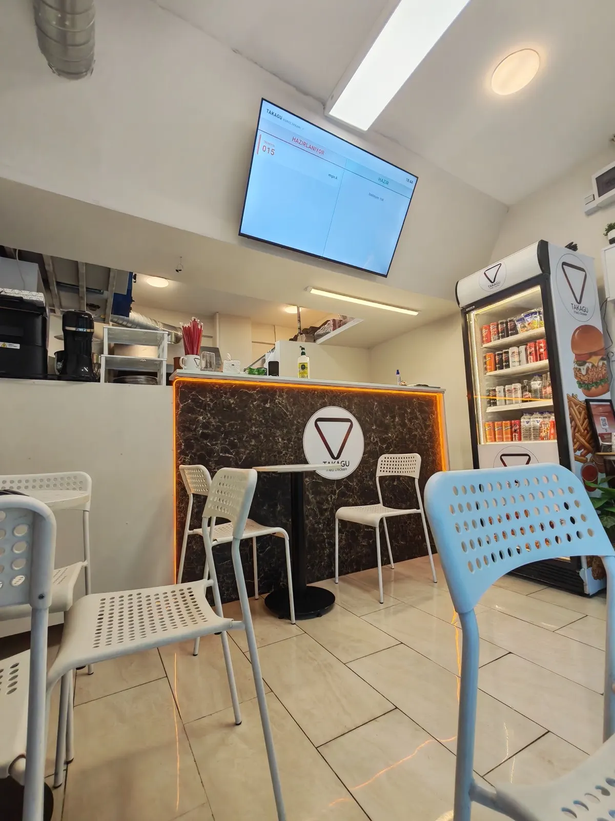 Inside the Takagu Fried Chicken shop in Üsküdar: counter, seating and menu screen